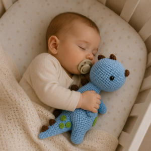 Bébé dormant paisiblement dans son berceau en serrant son doudou dino crochet.