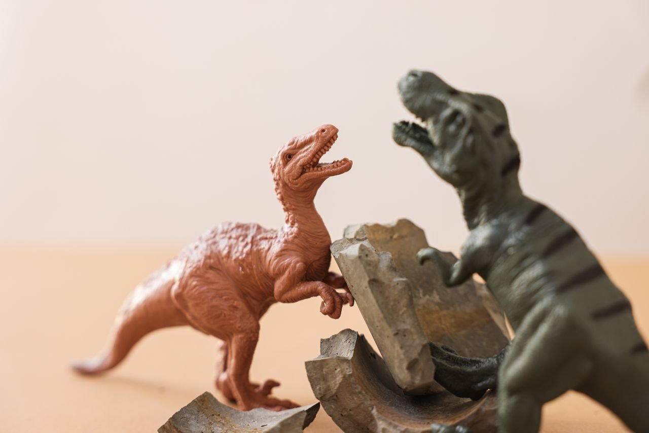 delivery-policy Close-up of colorful dinosaur figurine toys engaged in a playful battle.